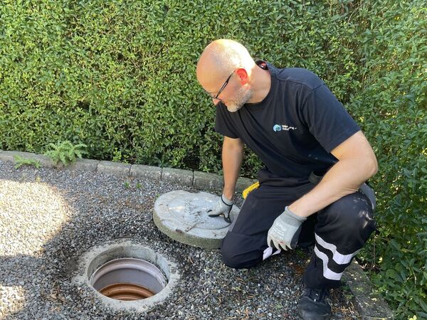 Mand kigger i regnvandsbrønd